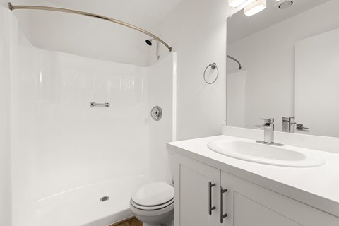 A white bathroom with a toilet, sink, and shower.