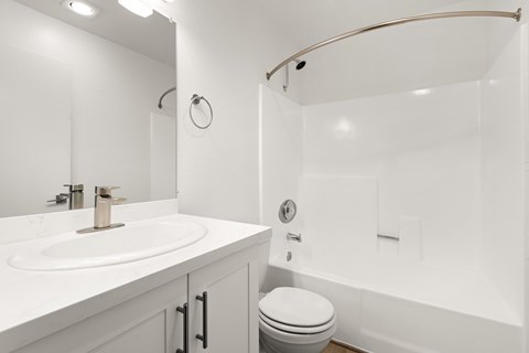 A white bathroom with a toilet, sink, and shower.