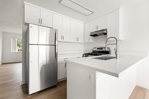 A modern kitchen with a stainless steel refrigerator and white cabinets.