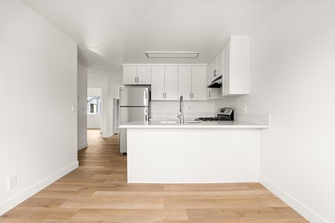 A kitchen with white cabinets and a wooden floor.