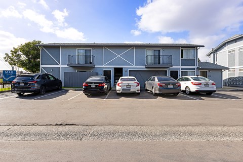 A parking lot with several cars parked in front of a building.