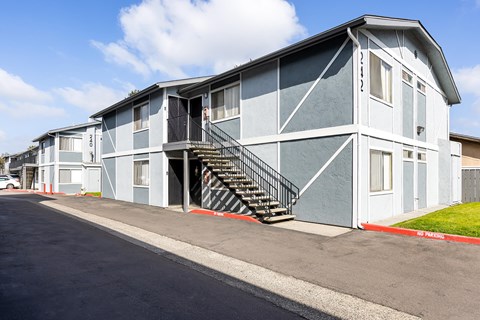 A grey and white building with a black metal staircase.