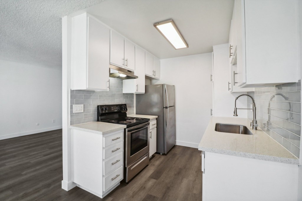 A kitchen with white cabinets and a stainless steel refrigerator.