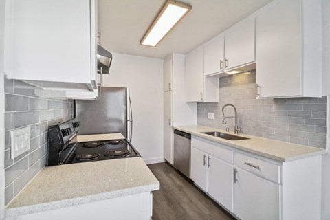 A kitchen with white cabinets and a tiled backsplash.