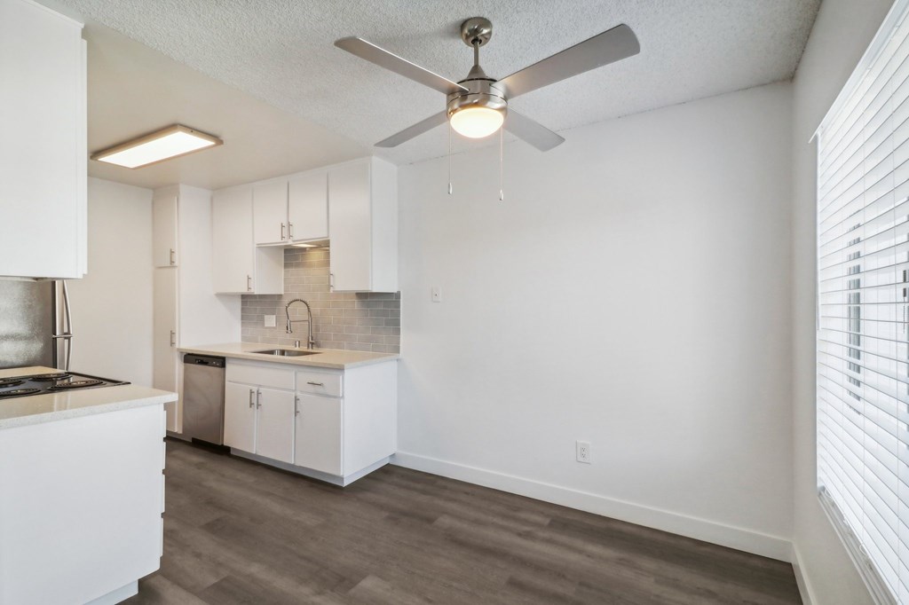 A kitchen with white cabinets and a fan.