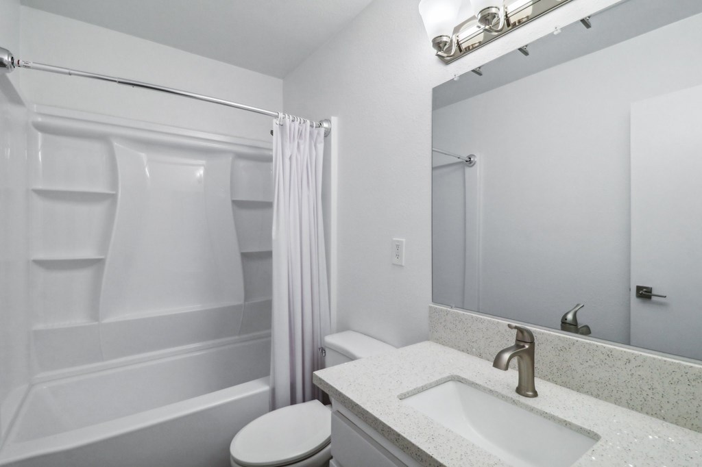 A white bathroom with a toilet, sink, and shower.