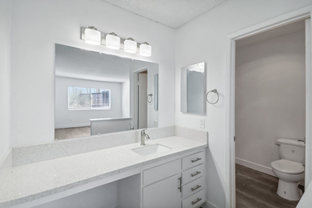 A bathroom with a white counter top and a white toilet.