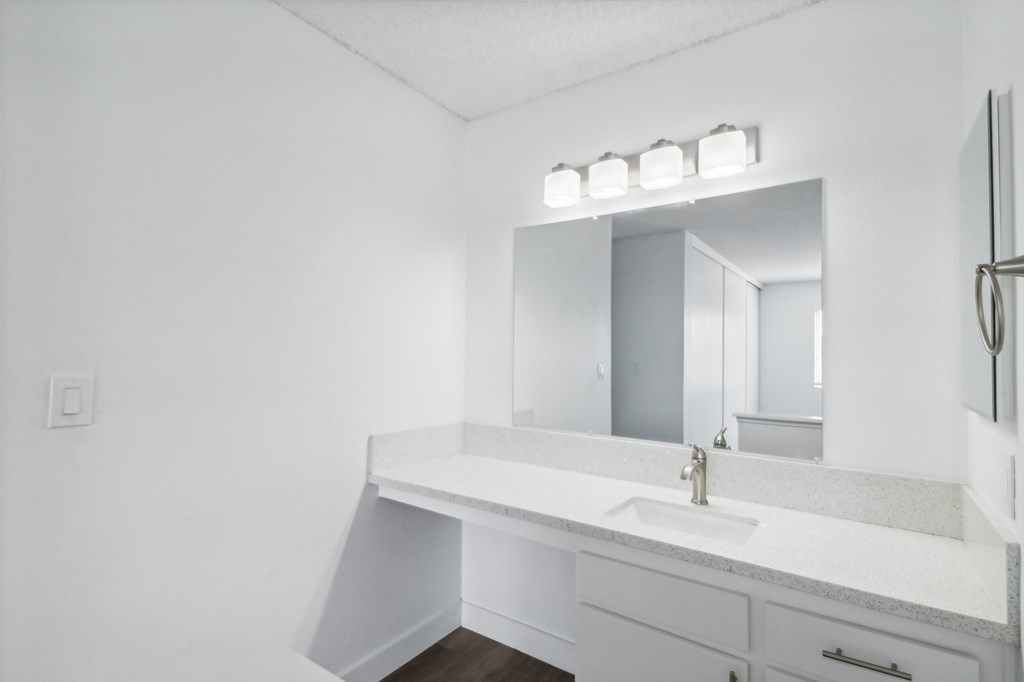 A white bathroom with a sink and mirror.
