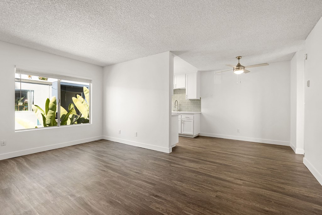 A spacious room with wooden flooring and a ceiling fan.