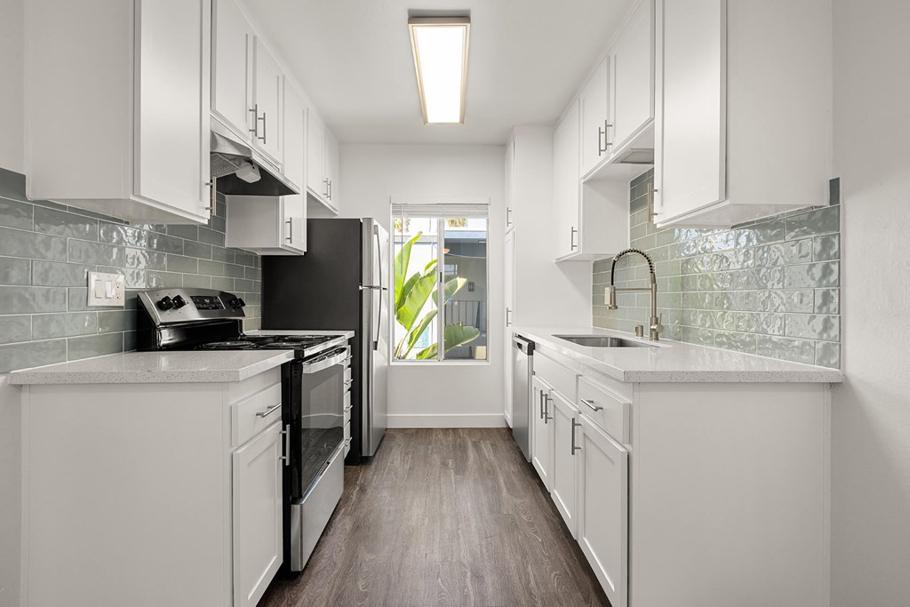 A modern kitchen with white cabinets and a black refrigerator.