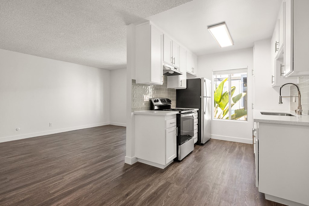 A kitchen with white cabinets and a black refrigerator.
