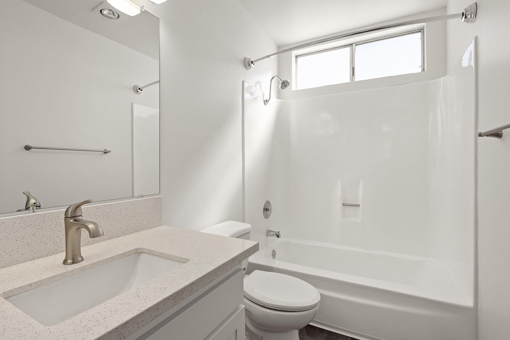 A white bathroom with a sink, toilet, and bathtub.