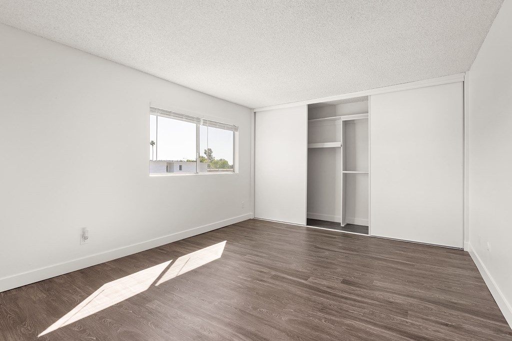 A room with a window and a door is empty and waiting to be furnished.