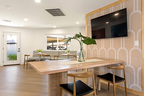 A dining area with a table, chairs, and a television mounted on the wall.