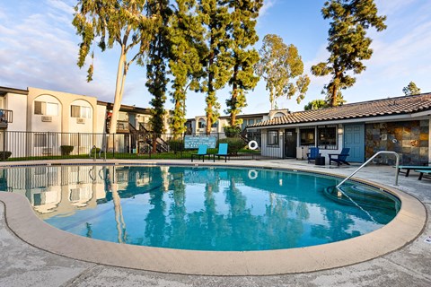 A swimming pool surrounded by trees and apartment buildings.