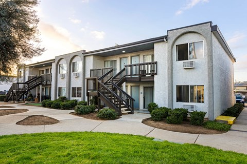 A white building with a balcony and stairs leading to the entrance.