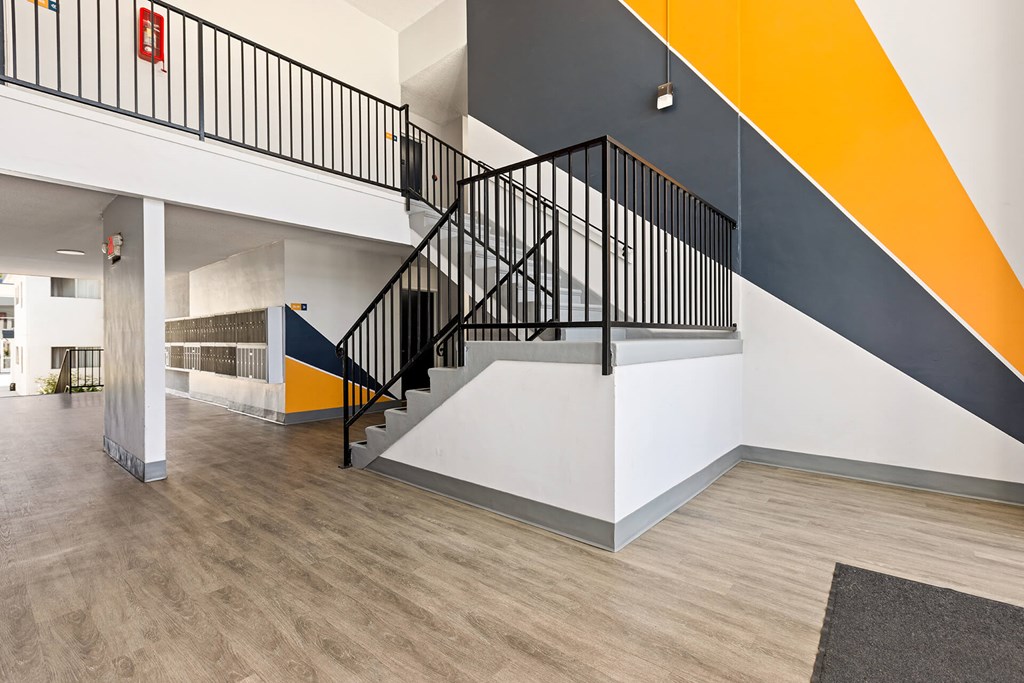 A staircase with a black railing and a yellow and grey wall.