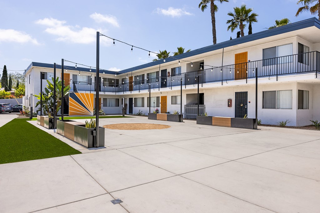 A modern building with a white and orange facade and a balcony with black railings.