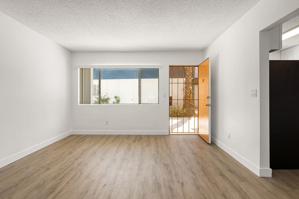 A room with a wooden floor and a door leading to a balcony.