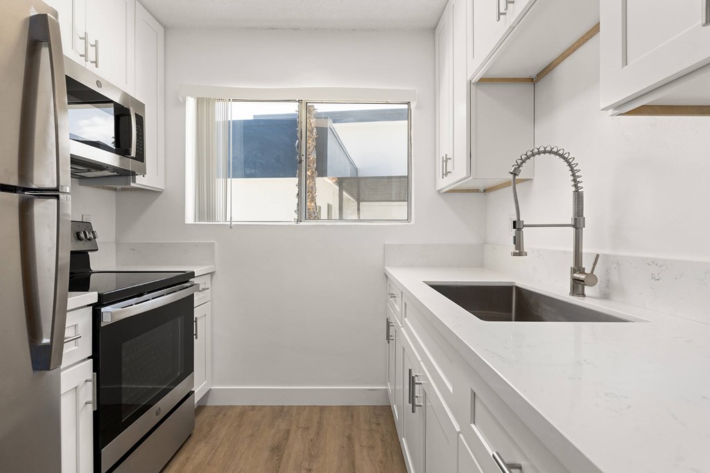 A modern kitchen with white cabinets and stainless steel appliances.