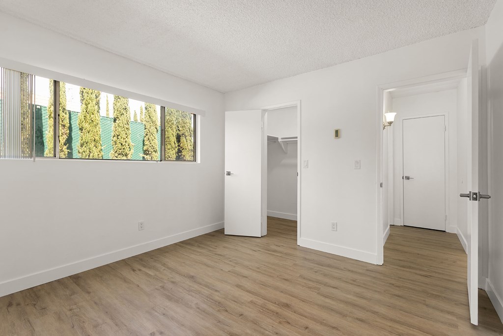 A white room with wood floors and a large window.