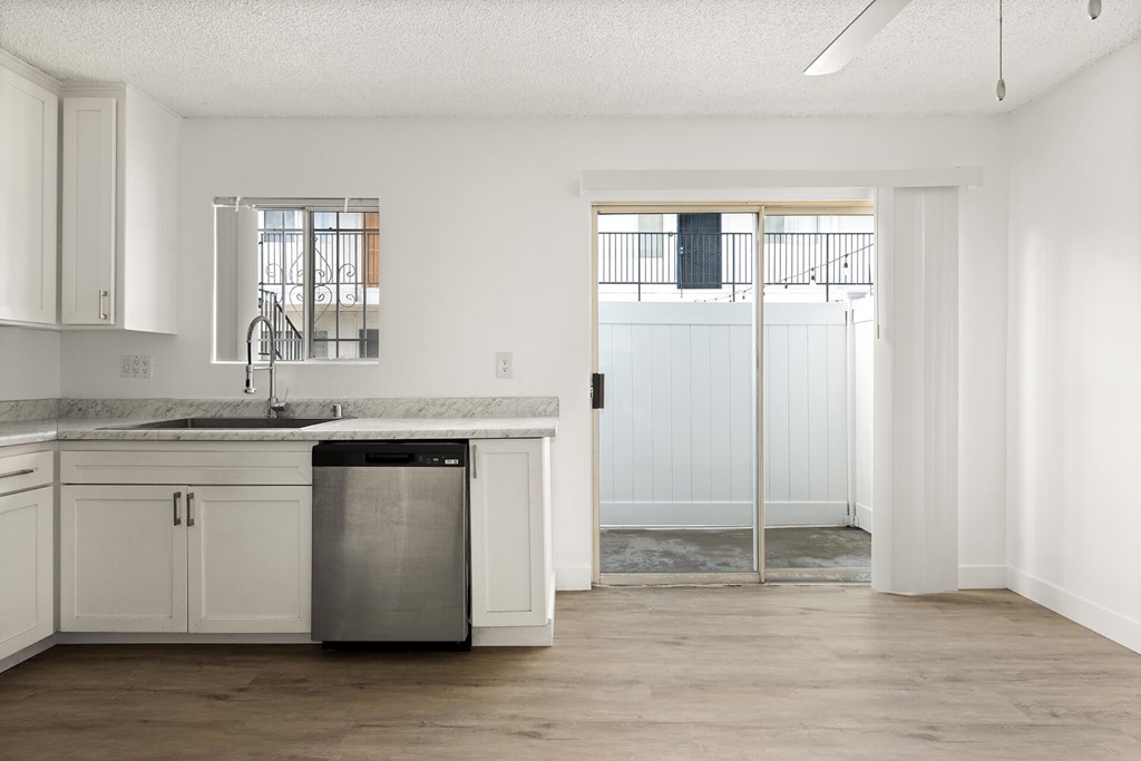 A kitchen with white cabinets and a marble countertop.