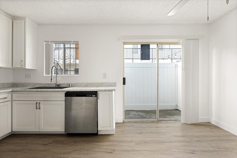 A kitchen with white cabinets and a marble countertop.