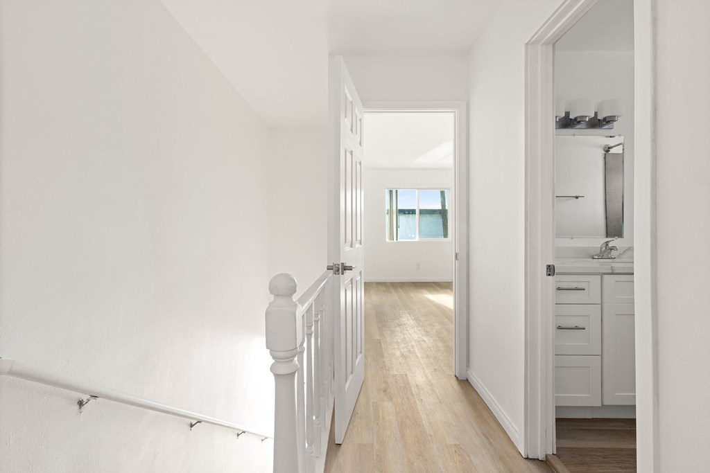 A white hallway leads to a kitchen.