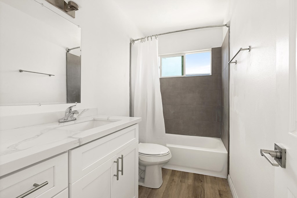 A white bathroom with a toilet, sink, and shower.