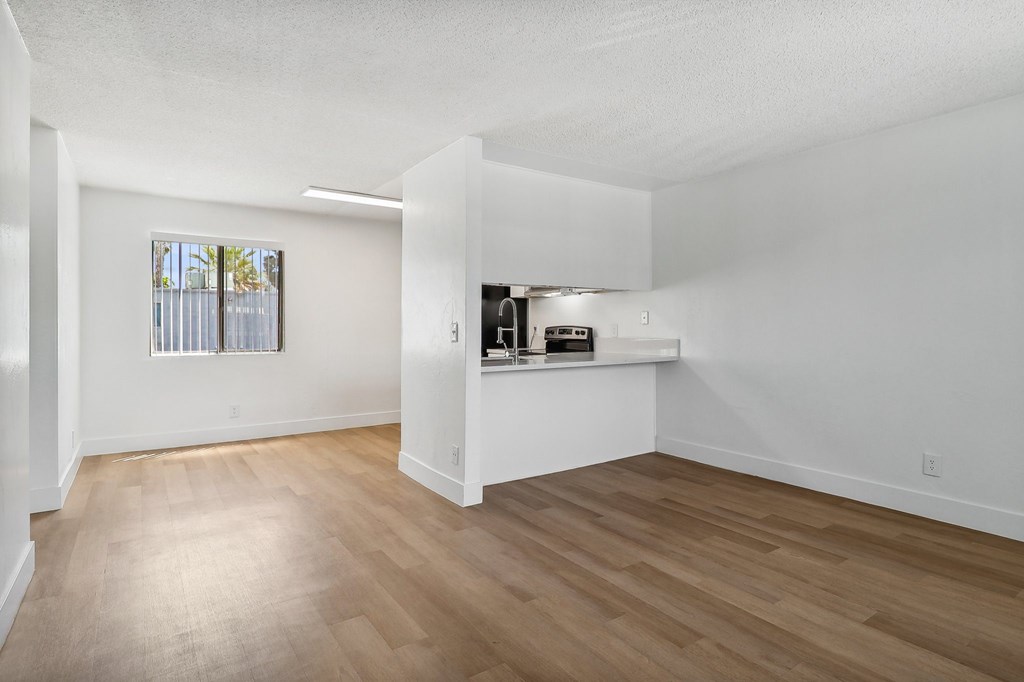 A room with wooden flooring and a window with blinds.