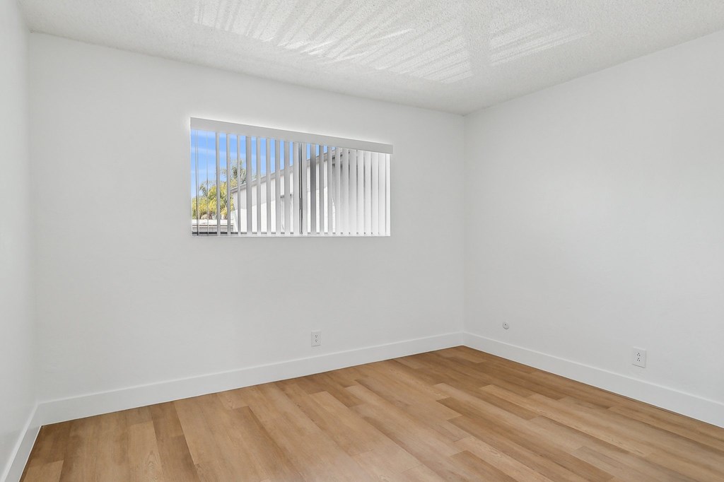 A room with a window and wooden flooring.