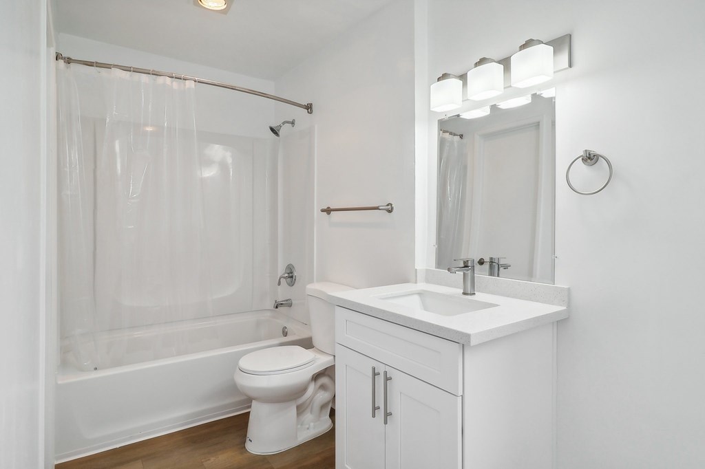 A white bathroom with a toilet, sink, and shower.