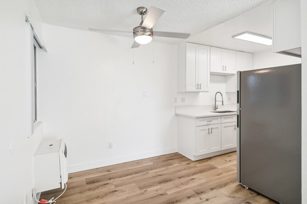 A kitchen with a refrigerator, sink, and cabinets.