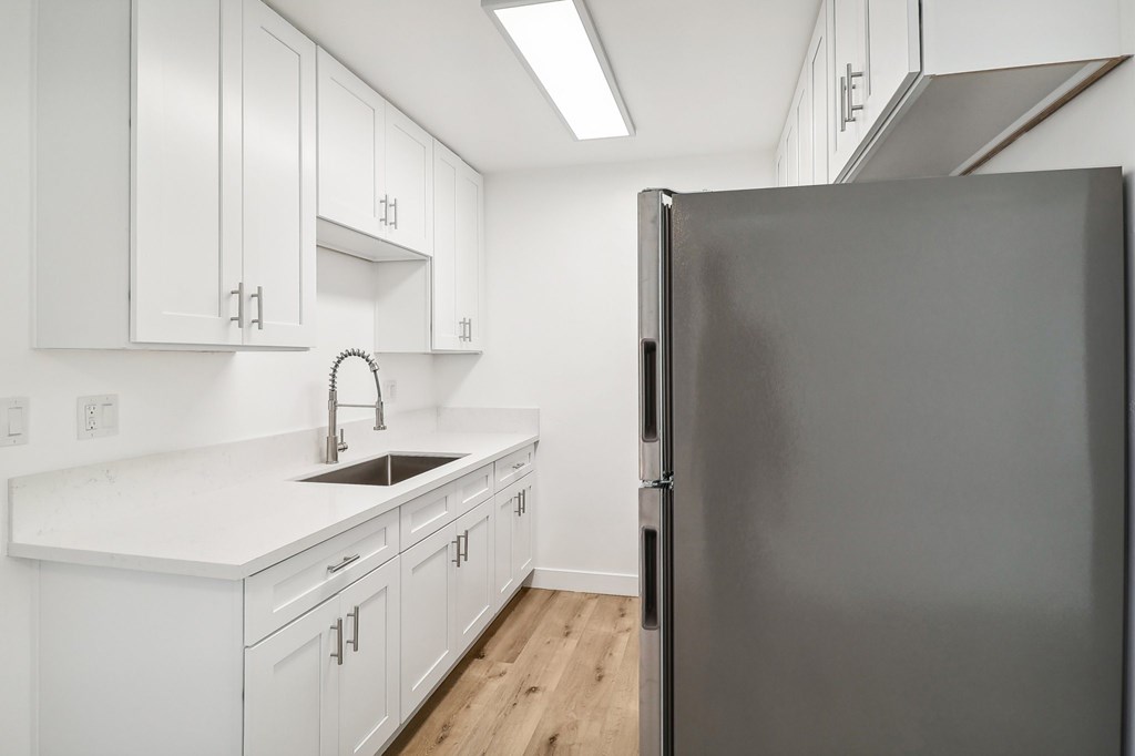 A modern kitchen with white cabinets and a black refrigerator.