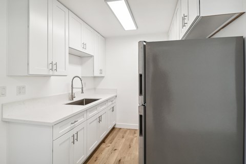 A modern kitchen with white cabinets and a black refrigerator.