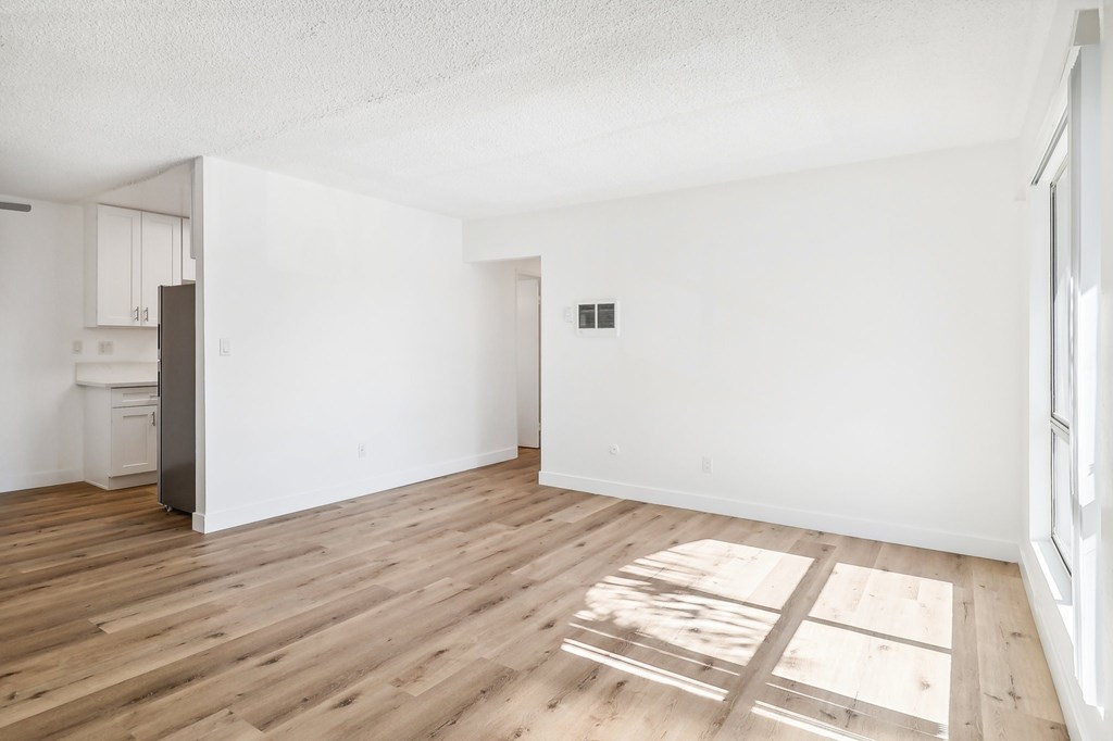A room with wooden flooring and white walls.