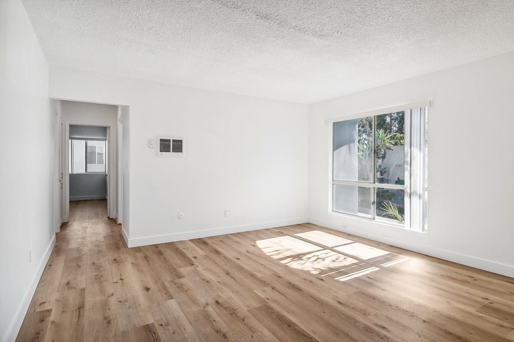 A room with wooden floors and a window showing trees outside.