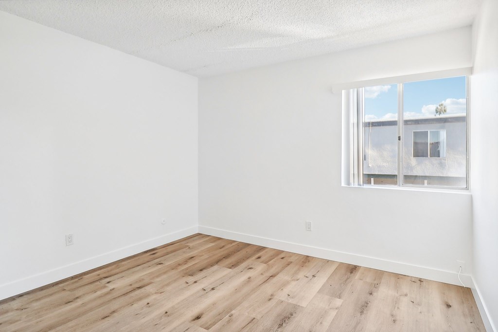 A room with a window and wooden flooring.