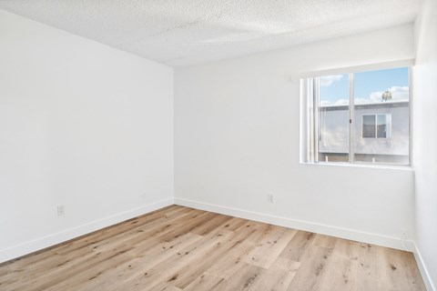 A room with a window and wooden flooring.