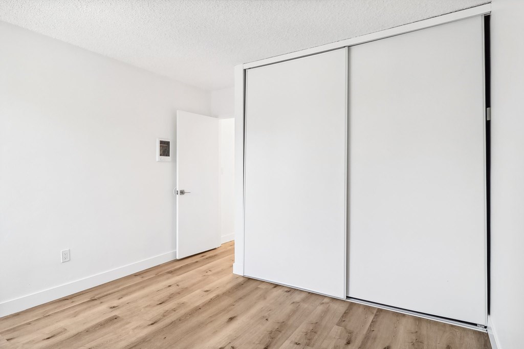 A white closet with a sliding door is in the corner of a room.
