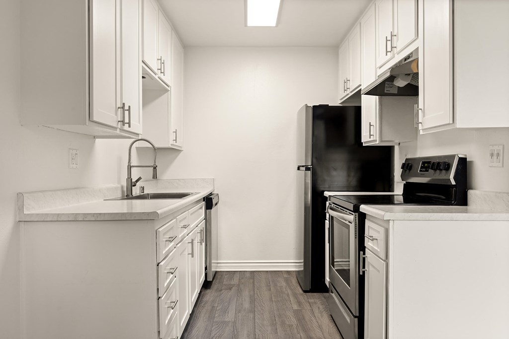 A kitchen with white cabinets and a black refrigerator.