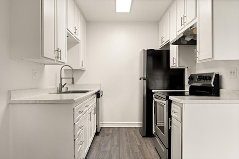 A kitchen with white cabinets and a black refrigerator.