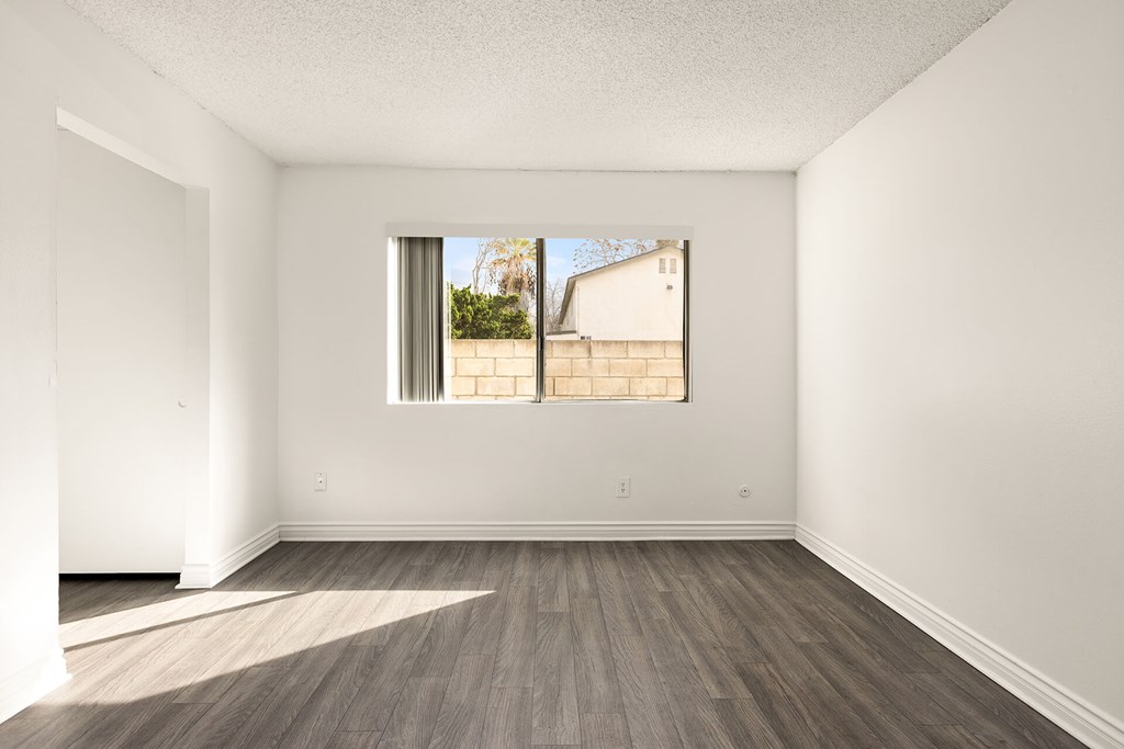 Empty room with a window and wooden flooring.