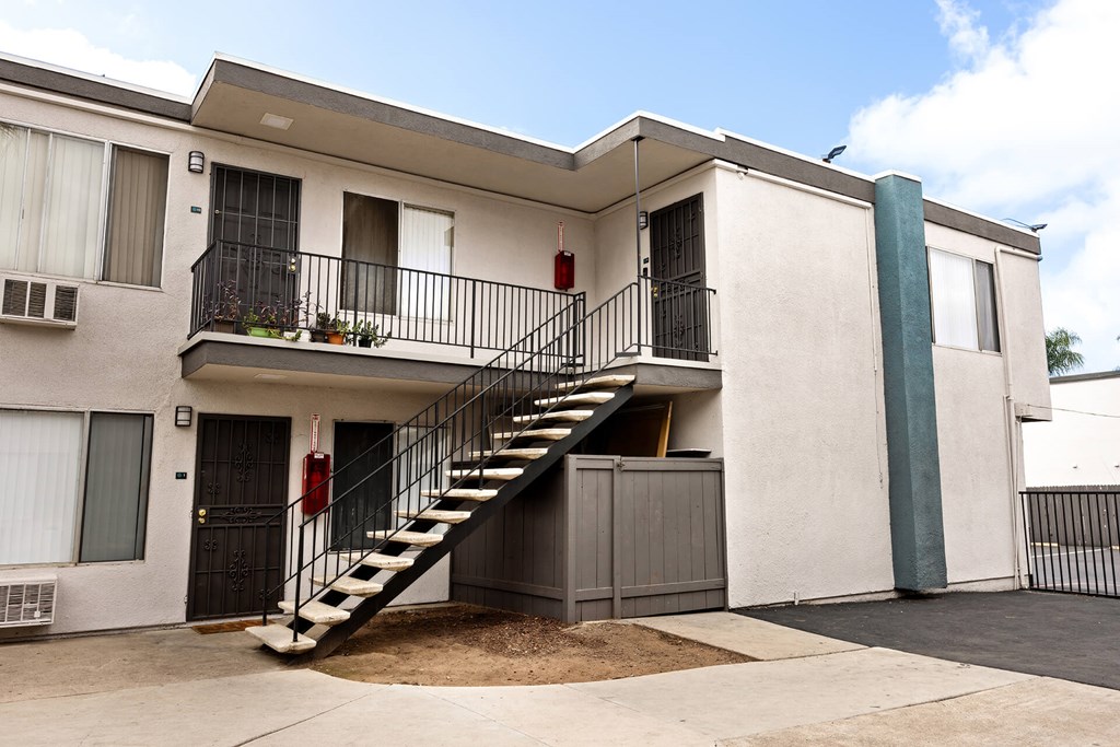 A white building with a red fire extinguisher on the balcony.