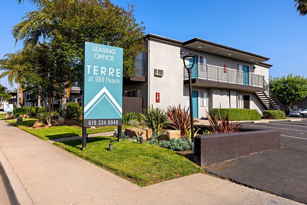 A leasing office sign for 989 Peach stands in front of a building.