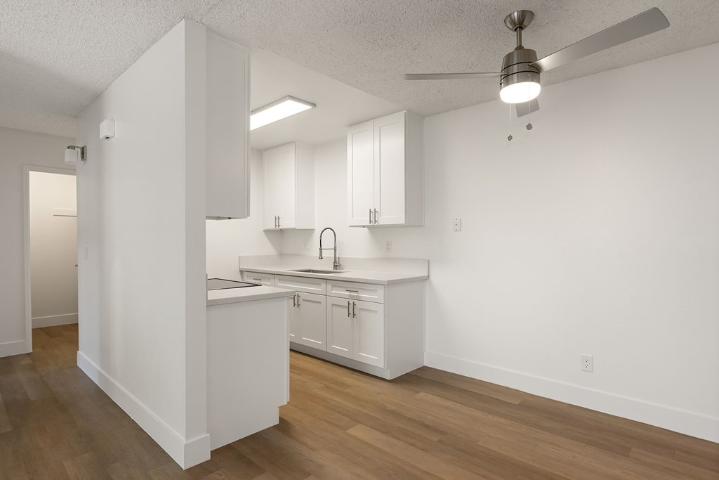 A kitchen with white cabinets and a wooden floor.