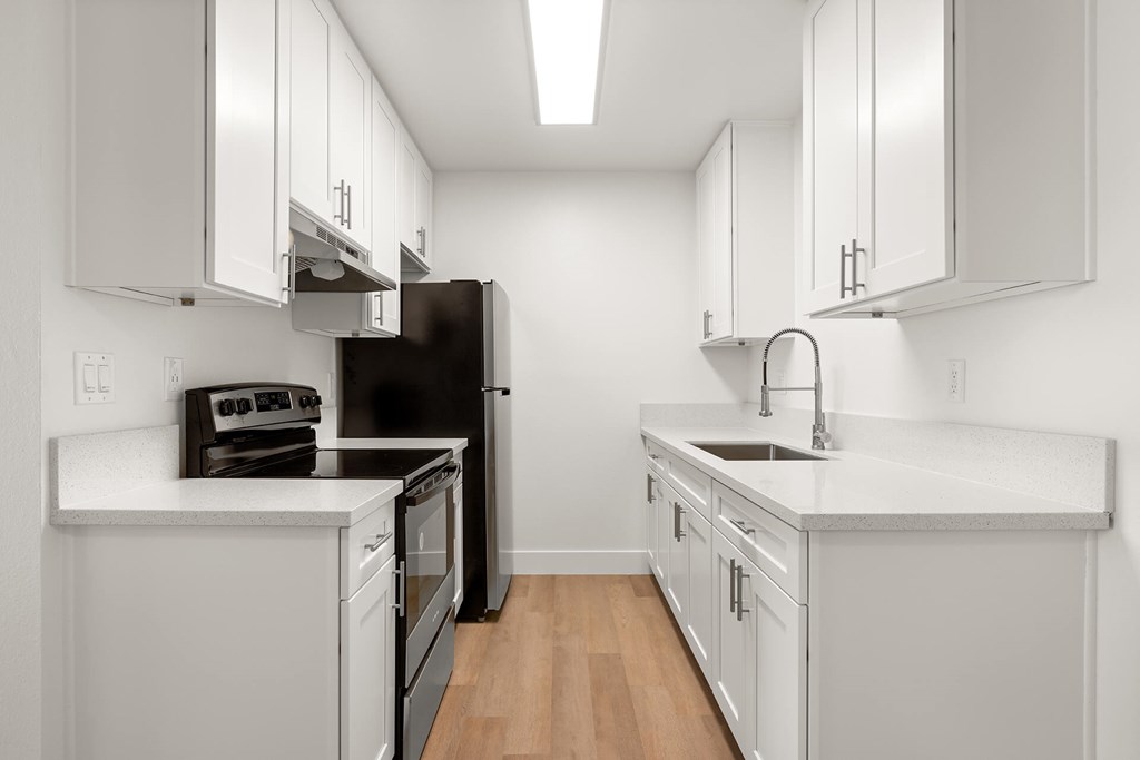 A kitchen with white cabinets and a black refrigerator.