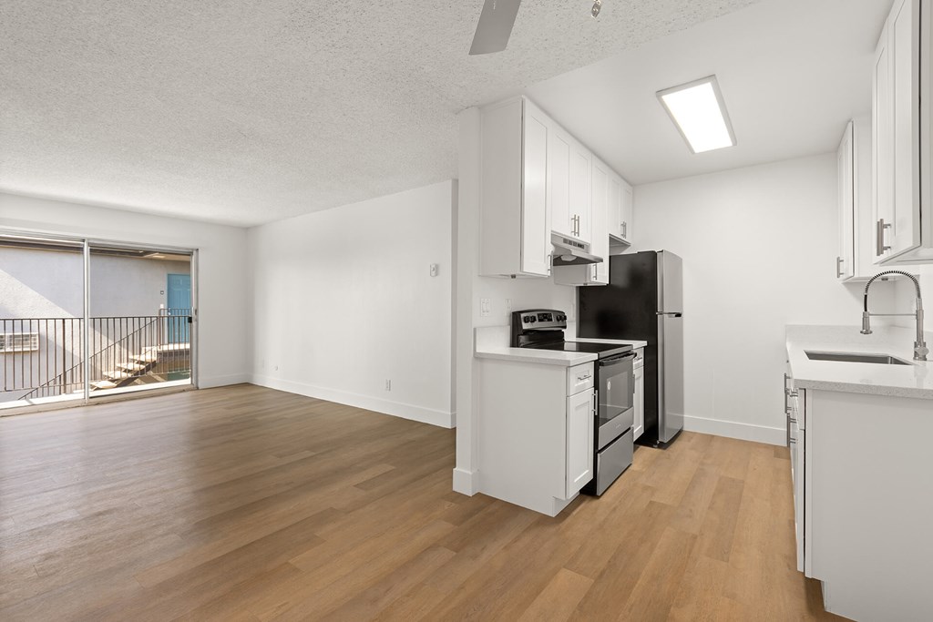 A kitchen with white cabinets and a black fridge.