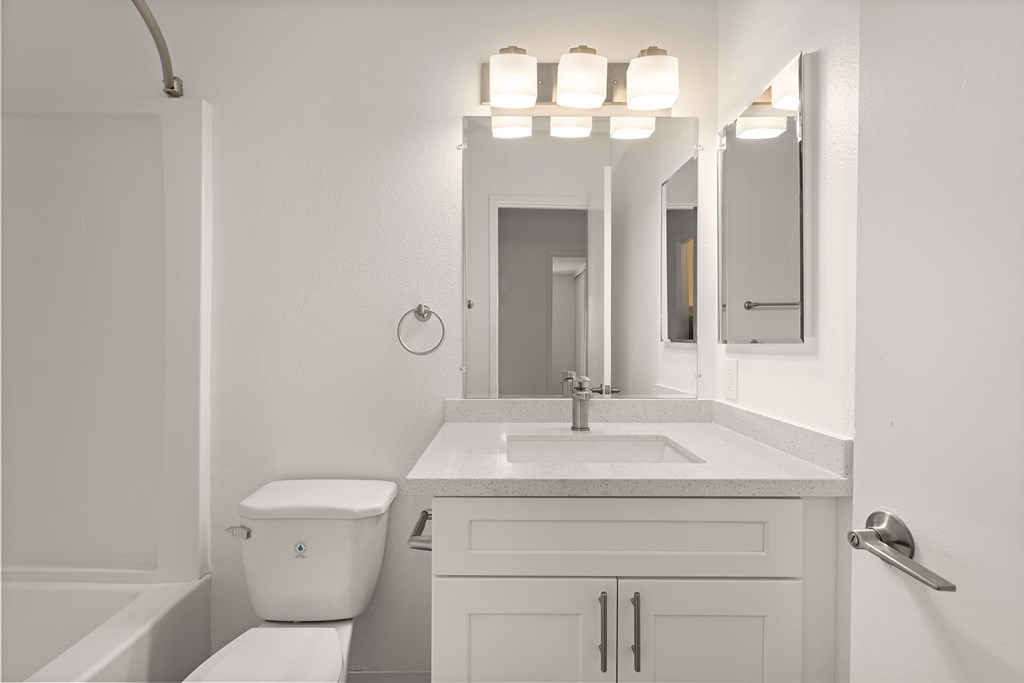 A white bathroom with a toilet, sink, and mirror.