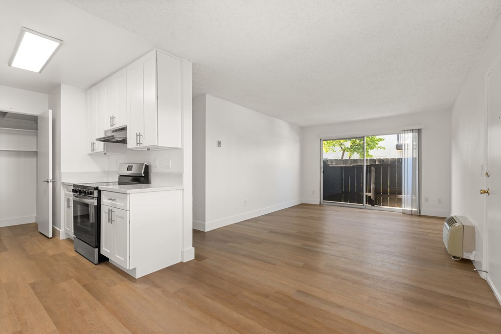 A kitchen with white cabinets and a wooden floor.